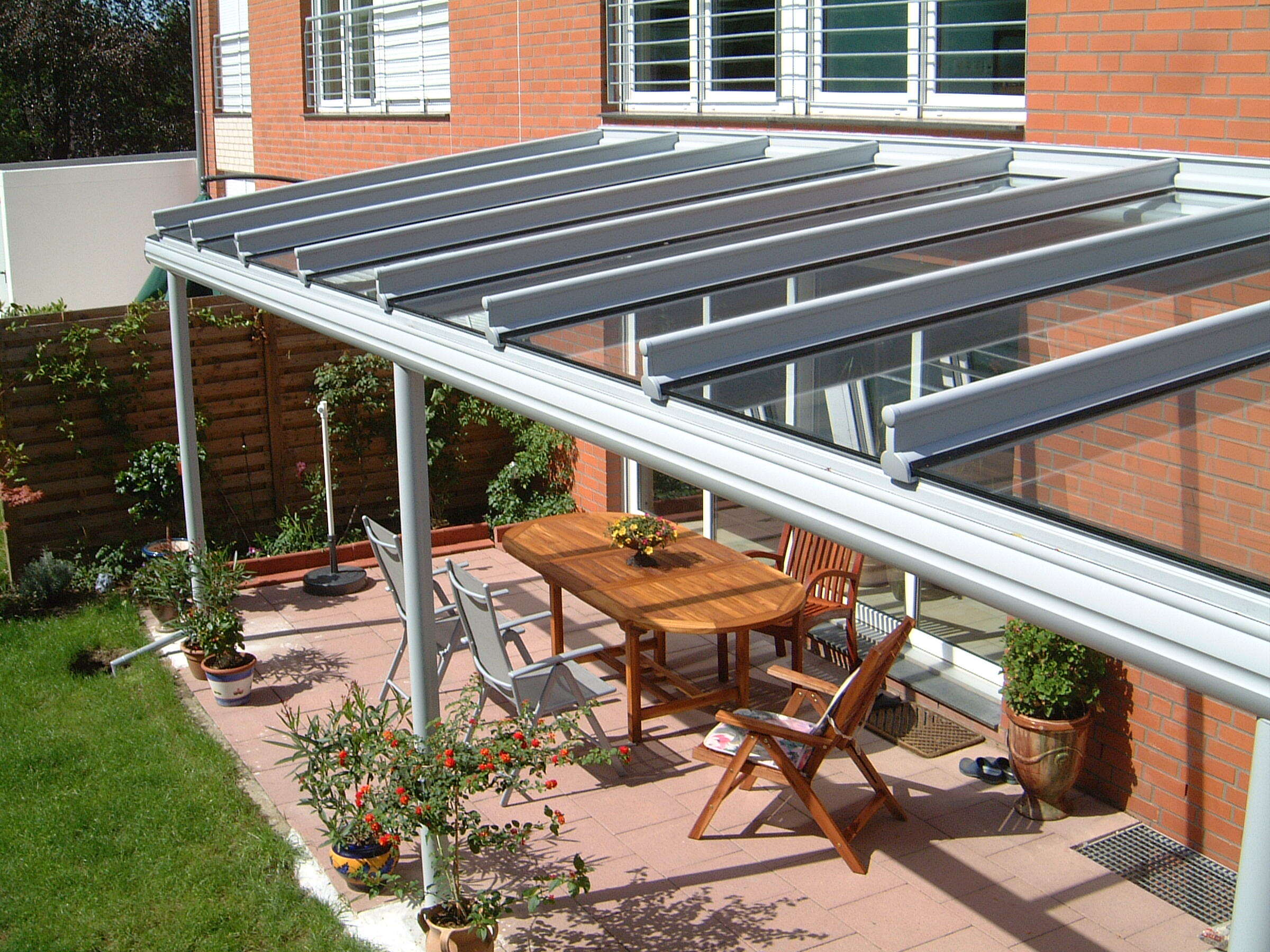Aluminium Terrassendach mit Glasscheiben über einer Terrasse mit Möbeln