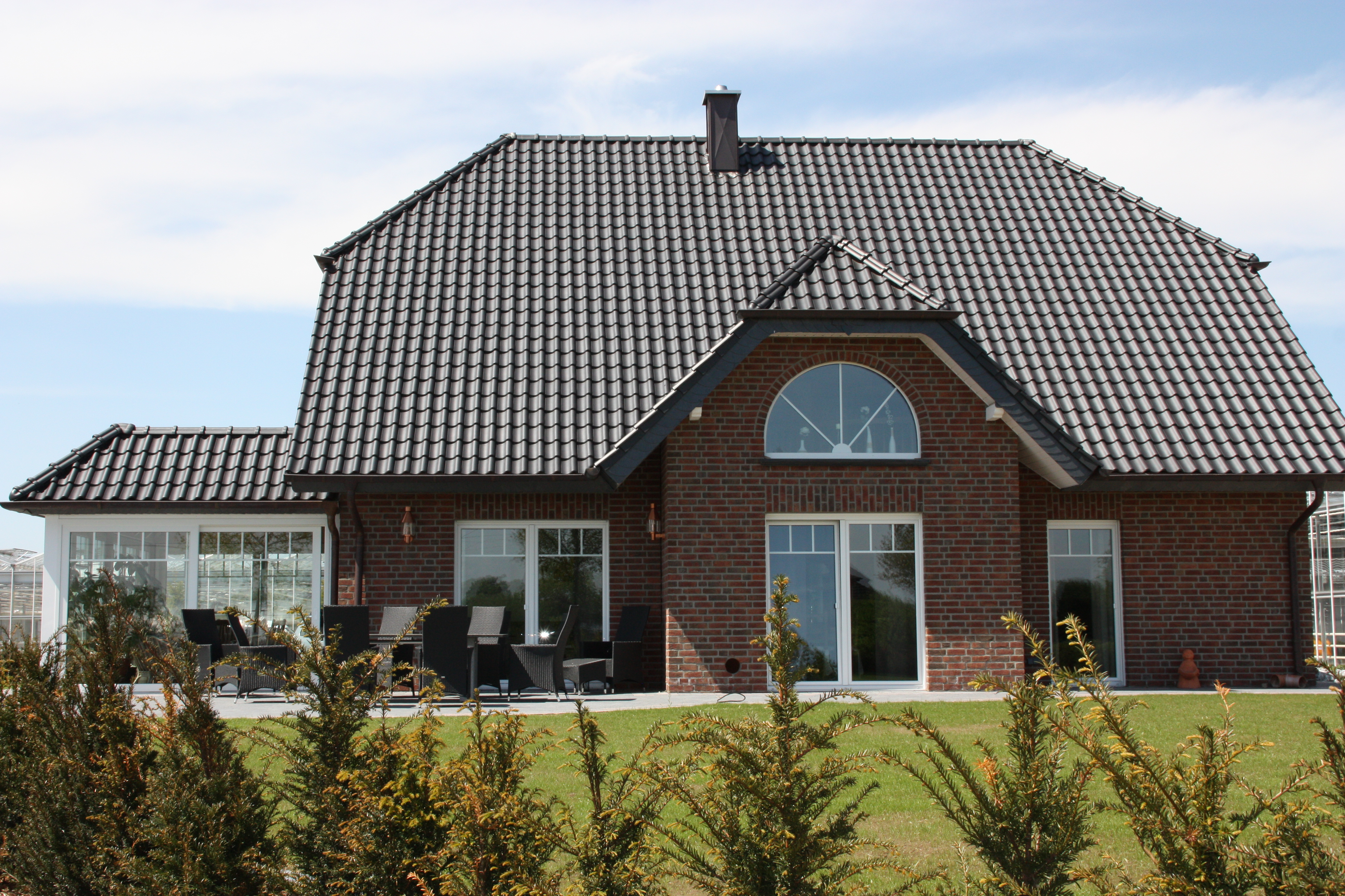 Außenansicht eines Hauses mit neuen Kunststofffenstern in weiß und einem Wintergarten