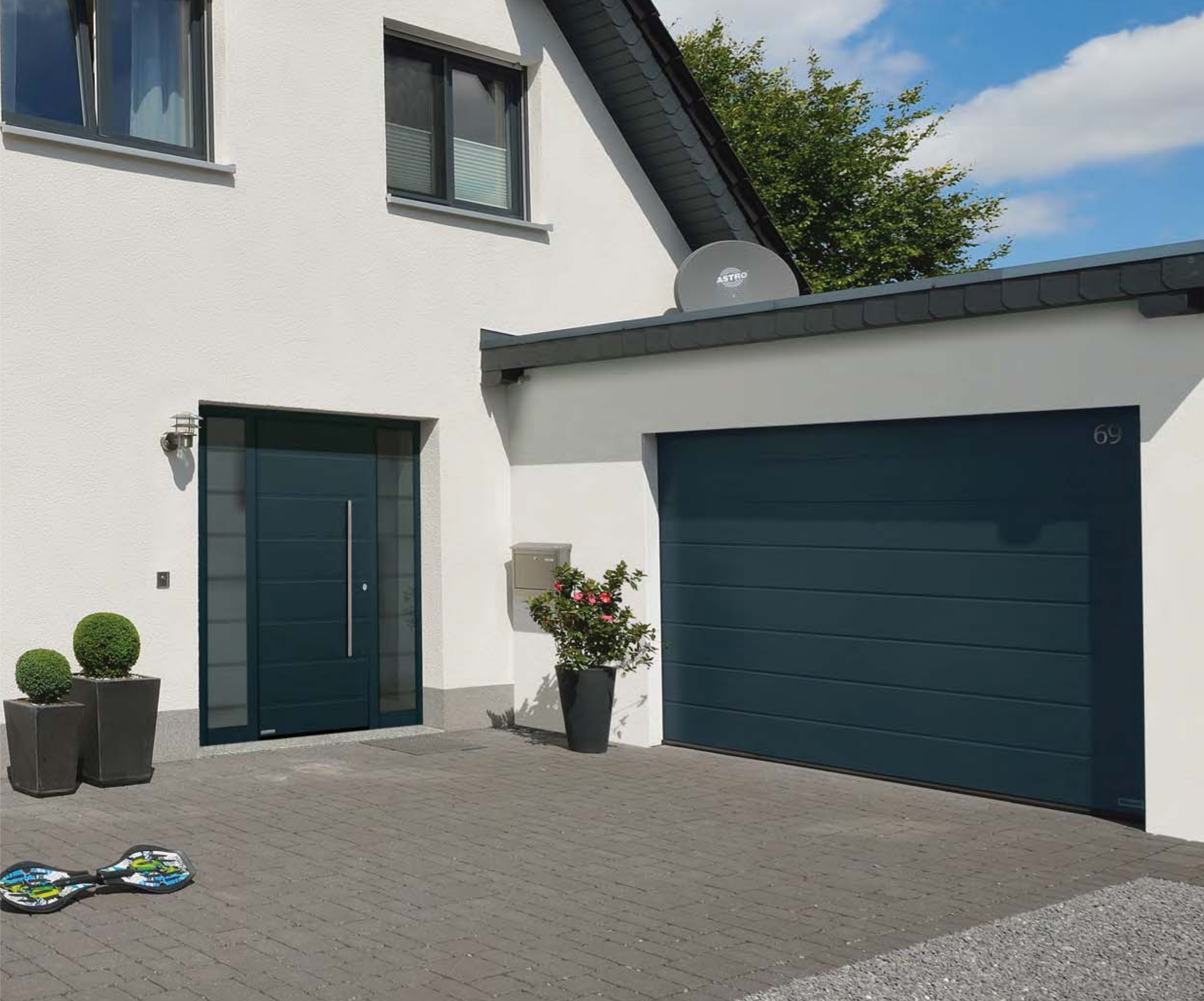Blaues Sektionaltor neben einer Haustür mit Seitenteil