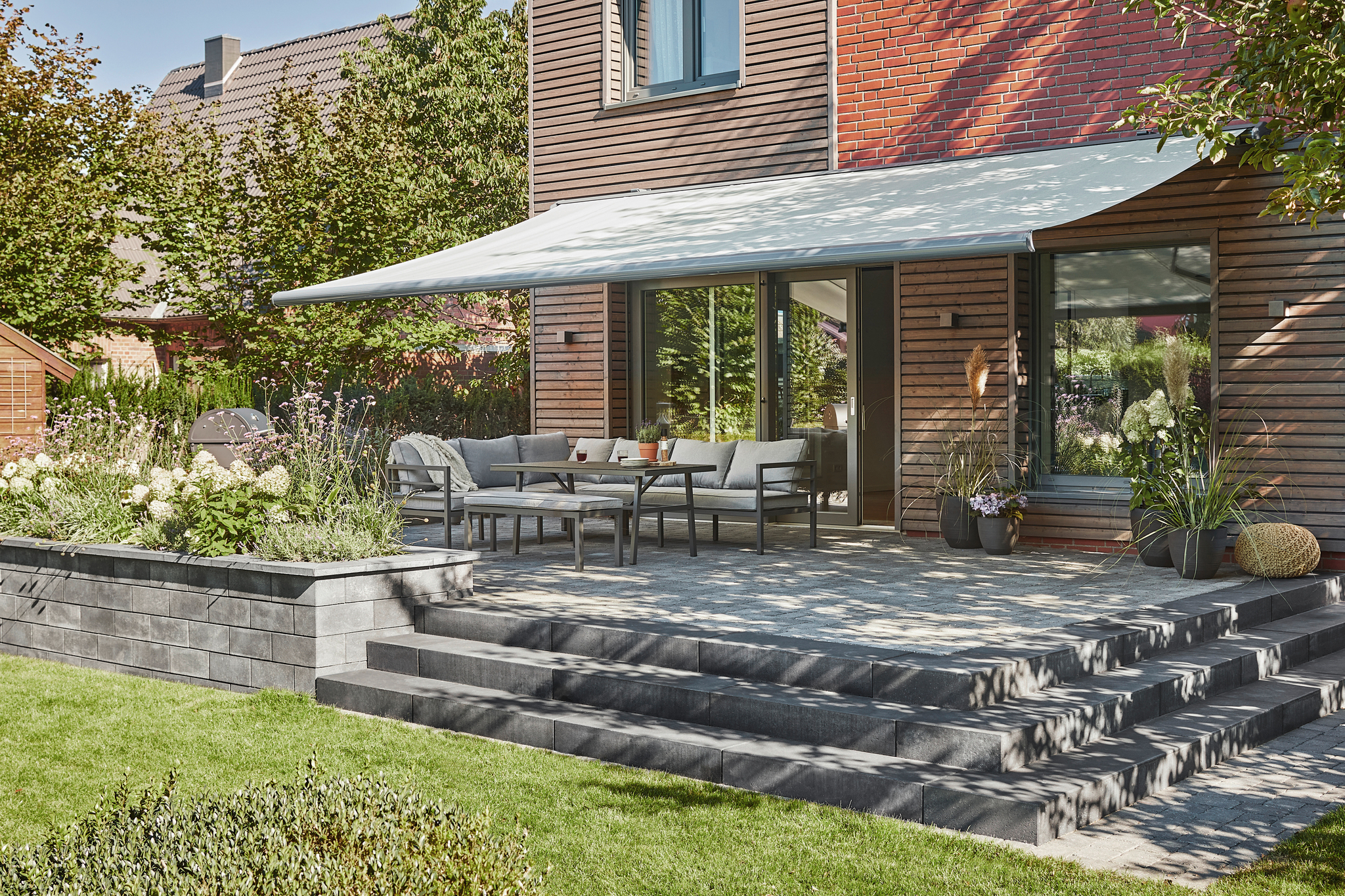 Warema Kassetten-Markise mit ausgefahrenem Markisentuch über Gartenmöbeln auf einer Terrasse